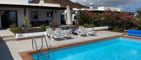 A swimming pool with lounge chairs and a small deck area.