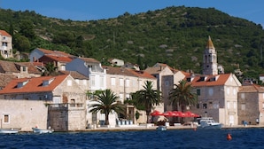 A coastal town with stone buildings, a church with a bell tower, and boats docked by the sea. - Luxury seafront villa, stunning sea & harbour views, on unspoilt island of Vis (Vis)