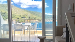 A room with a view of a coastal landscape, featuring a round table and chairs, a sofa, and a small table. - Luxury seafront villa, stunning sea & harbour views, on unspoilt island of Vis (Vis)
