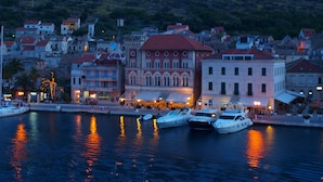 A waterfront area with boats docked, buildings with red roofs, and a hill in the background. - Luxury seafront villa, stunning sea & harbour views, on unspoilt island of Vis (Vis)