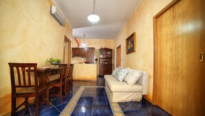 A dining area with a table and chairs, a sofa, and a kitchen in the background. - VILLA SEA SALENTO (Marina San Gregorio)