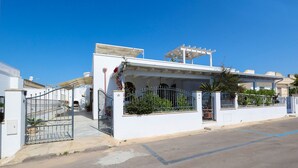 A residential building with a gated entrance, a covered porch, and a clear blue sky. - VILLA SEA SALENTO (Marina San Gregorio)