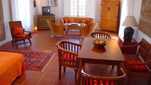 Una habitació amb taula de menjador, cadires, sofà, televisió i un armari.