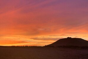 A sunset over a hill with a structure on top, possibly a fort or lookout. - Enchanting and Spacious Holiday Cottage Chimida in Historic Teguise Vi (Costa Teguise)