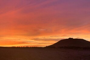 Tramonto su una collina con una struttura in cima, forse un forte o un punto panoramico.