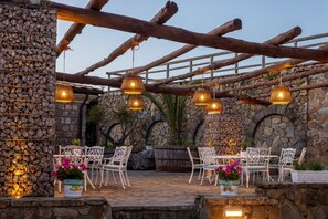 An outdoor patio with stone walls, wooden beams, and hanging pendant lights.