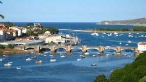 Une ville côtière avec un pont enjambant l’eau, des bateaux et des bâtiments le long de la rive.