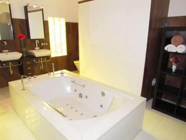 Un baño moderno con una bañera grande, un tocador doble y un espejo sobre el lavabo.