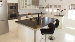 Una cocina moderna con electrodomésticos de acero inoxidable, una isla central y un taburete negro.
