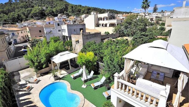 Piscina en la azotea con sillones reclinables y una zona de estar cubierta, rodeada de edificios y vegetación.