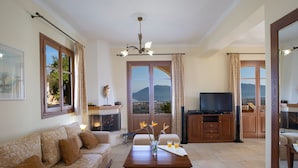 A living room with a sofa set, a coffee table, a fireplace, and a television. - Luxury stone-made villa with exceptional view & pool (Lefkada)