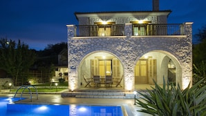 A stone building with a swimming pool, two balconies, and arched doorways. - Luxury stone-made villa with exceptional view & pool (Lefkada)