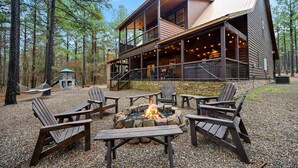 A cabin with a fire pit and outdoor seating. - Luxury Broken Bow Cabin w/ Game Room & Hot Tub | Sleeps 16 (HOCHATOWN)
