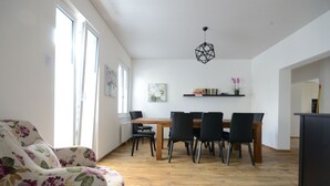 A dining area with a wooden table and chairs, a floral sofa, and a hanging light fixture.