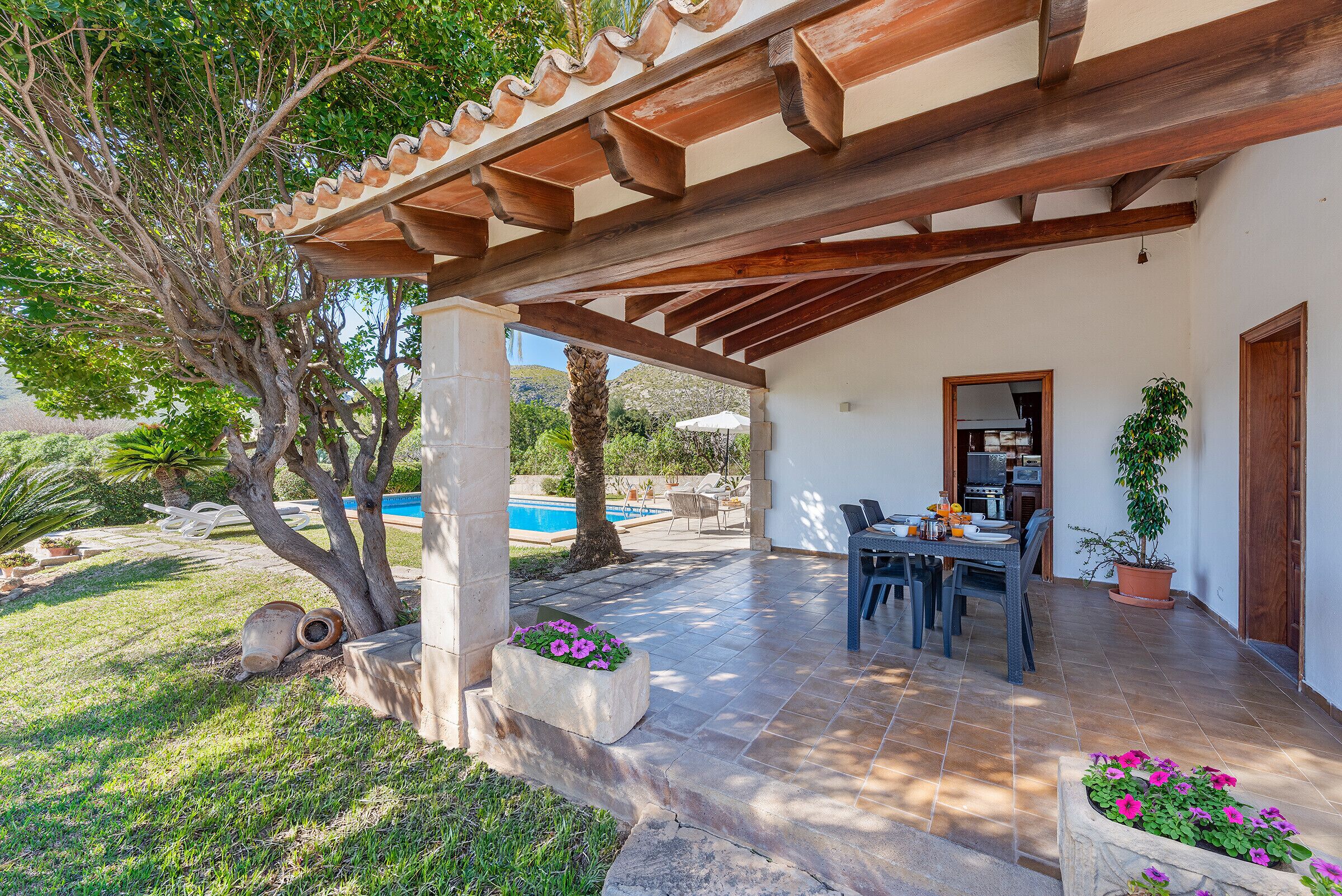 Un patio coperto con piscina, mobili da esterno e piante in vaso.