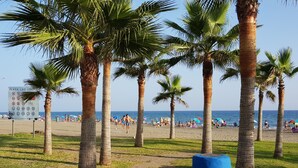 A beach with palm trees, a sign with beach rules, and people relaxing on the sand. - Enjoy the sun, sand and salty sea in a stylish floor on the first line (Torrox)