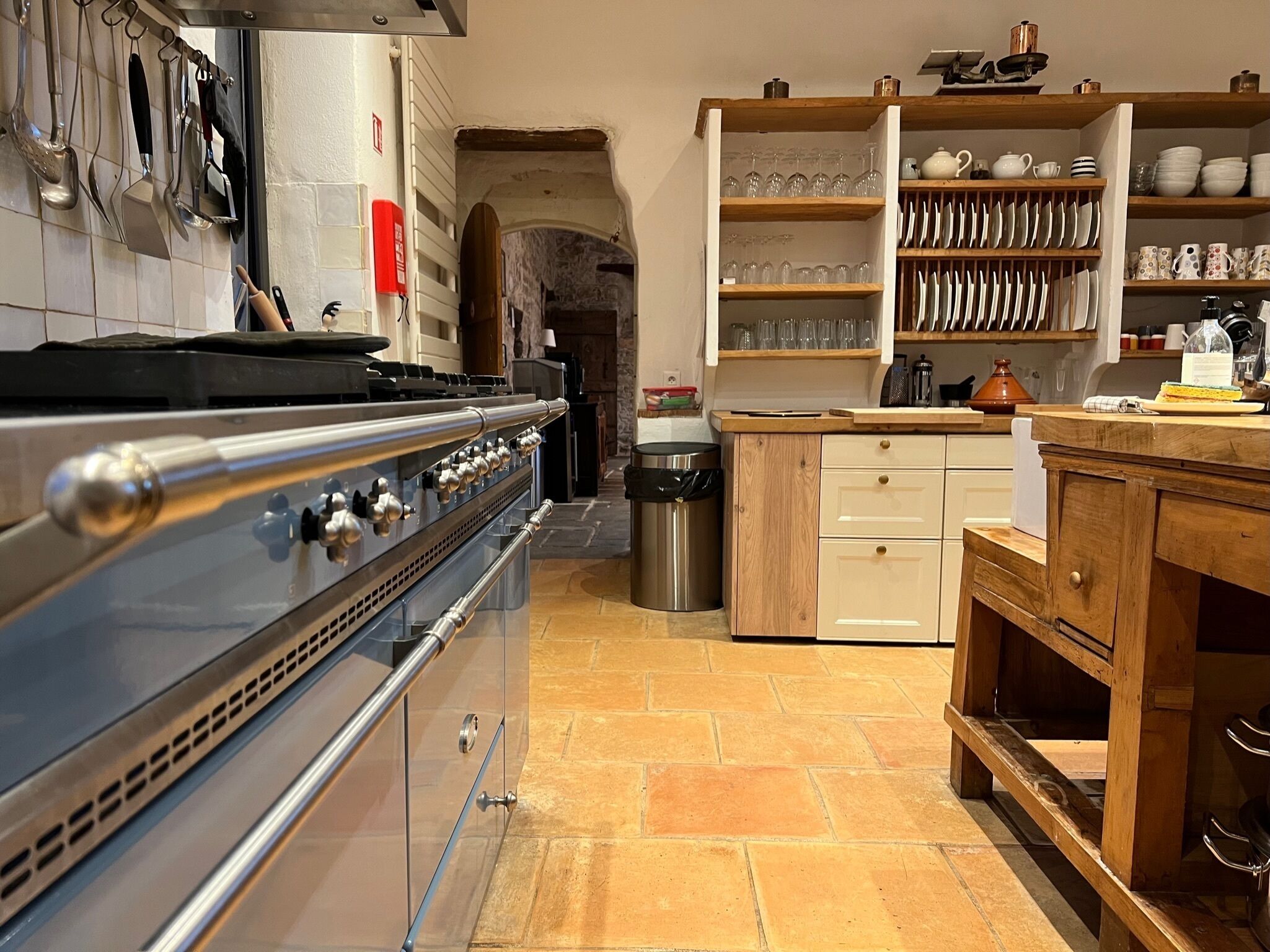 A kitchen with a stainless steel stove, wooden cabinets, and a tiled floor.