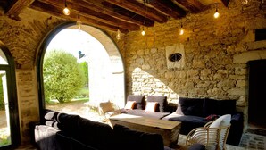 Une pièce chaleureuse avec un mur en pierre, une grande fenêtre en arc de cercle et un plafond en bois.