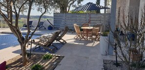 A poolside area with lounge chairs, a table, and a pergola with a striped awning. - Character house with swimming pool in medieval village (Lauzerte)