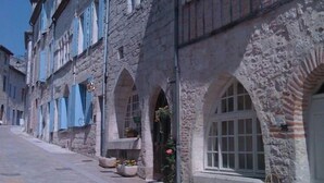 Een historische straat met stenen gebouwen, rondboogvensters en een verharde weg.