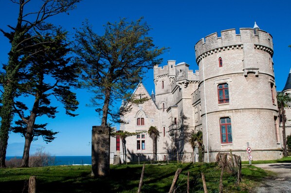 A castle with a round tower, large windows, and a view of the sea. - Beachfront Apartment In Hendaye Plage (Hendaye)