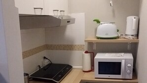 A compact kitchen with a microwave, toaster, and a small stool. - Lake Maggiore Apartment (Villaggi)