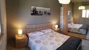 A bedroom with a bed, nightstands, a mirror, and a painting on the wall. - Lake Maggiore Apartment (Villaggi)