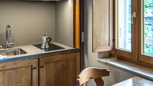 Une cuisine avec des meubles de rangement en bois, un évier en acier inoxydable et une fenêtre avec une porte ouverte.