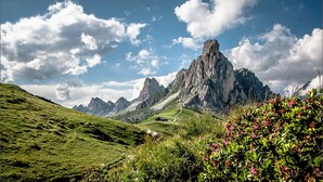 Un paysage montagneux caractérisé par un sommet rocheux imposant, une route sinueuse et une végétation luxuriante.