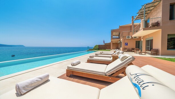 A poolside area with sun loungers and a view of the sea.