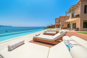 Ein Poolbereich mit Liegestühlen und Blick aufs Meer.