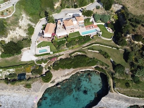 An aerial view of a coastal property with a swimming pool, multiple buildings, and a beach area. - Seafront Villa with Panoramic Views, 5 Bedrooms, Pool, 3 Min Walk to Sandy Beach (Kefalonia)