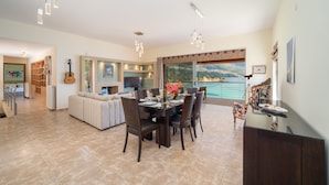 A spacious dining area with a large table and chairs, a sofa, and a view of the ocean.