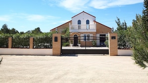 A two-story house with a gated entrance, a balcony, and a red roof. - The Palms - Spacious Private Villa For Family  Fun & Relaxation (L'Ametlla de Mar)