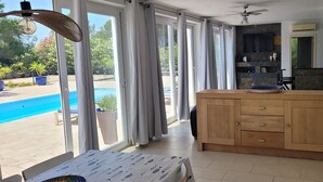 A room with a wooden cabinet, a dining table, and a view of a swimming pool. - The Palms - Spacious Private Villa For Family  Fun & Relaxation (L'Ametlla de Mar)