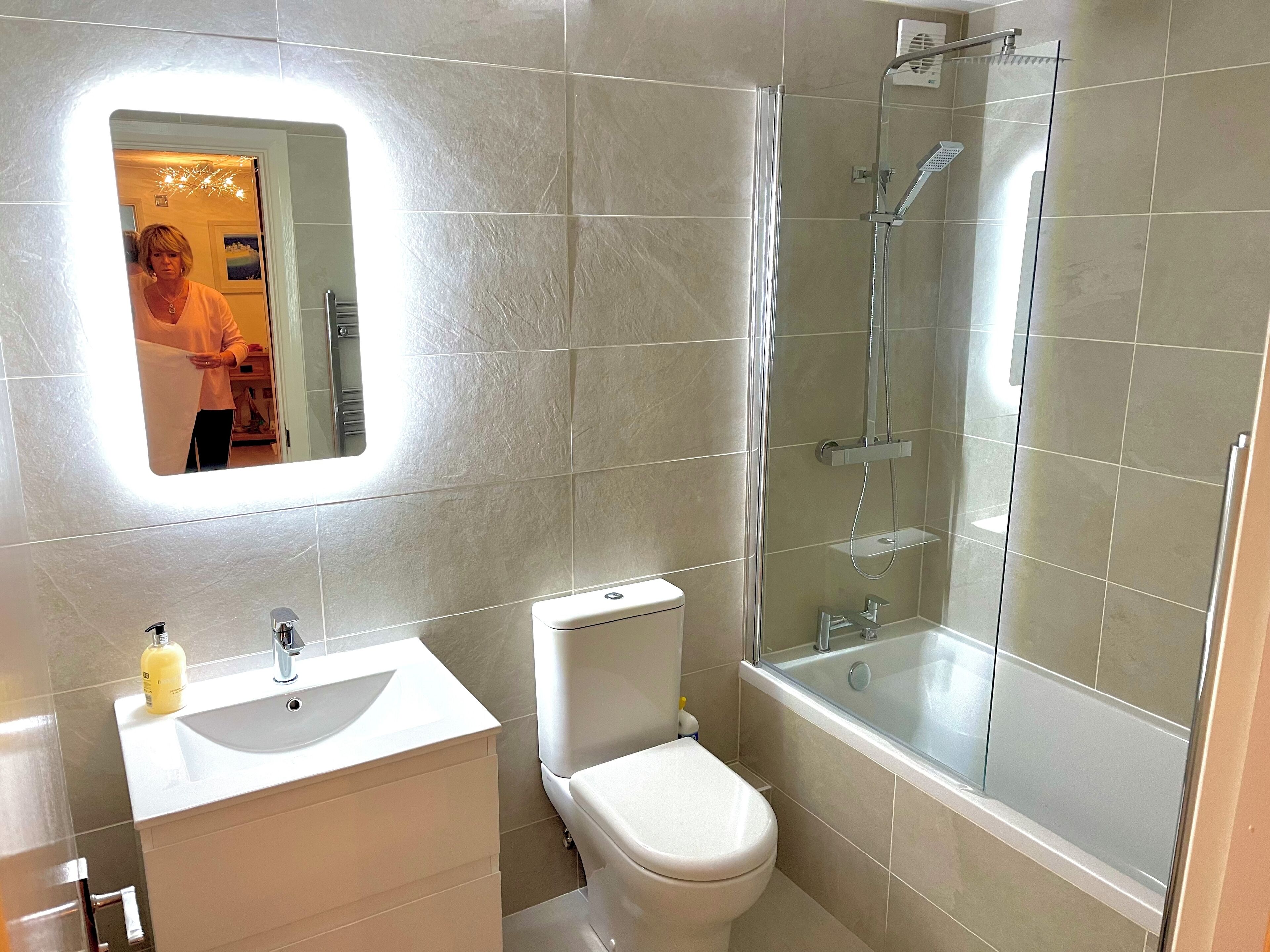 A modern bathroom with a white sink, toilet, and glass-enclosed shower.