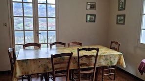 A dining area with a table and chairs, a view through a large window, and framed pictures on the wall. - House / Villa - Lescun (Lescun)