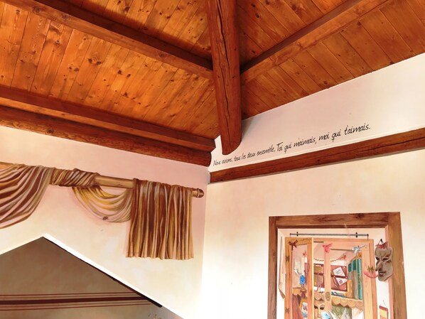 Ein Zimmer mit Holzbalken, einem Vorhang und einer Wand mit Text.