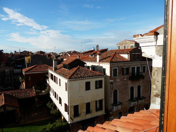 A view of a densely packed urban area with traditional buildings featuring red-tiled roofs and white facades. - Romantic "on the roof", view of a little canale (Venezia)
