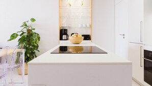 A modern kitchen with white cabinetry, a central island, a coffee machine, and a potted plant. - Hot pool, sea, wifi pro, gas barbecue, garden, 09 (San Miguel de Abona)
