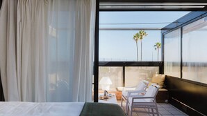 A modern hotel room with a large bed, a balcony with a seating area, and a view of palm trees. - Hot pool, sea, wifi pro, gas barbecue, garden, 09 (San Miguel de Abona)