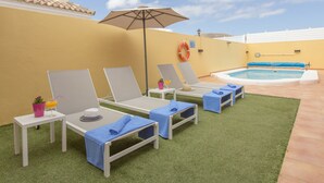 A poolside area with lounge chairs, a small table with a drink, and a lifebuoy on the wall. -  VILLA "BELLA LUCIA 1" PRIVATE HEATED POOL, WIFI, BARBECUE, SATELLITE TV  (corralejo- la oliva)