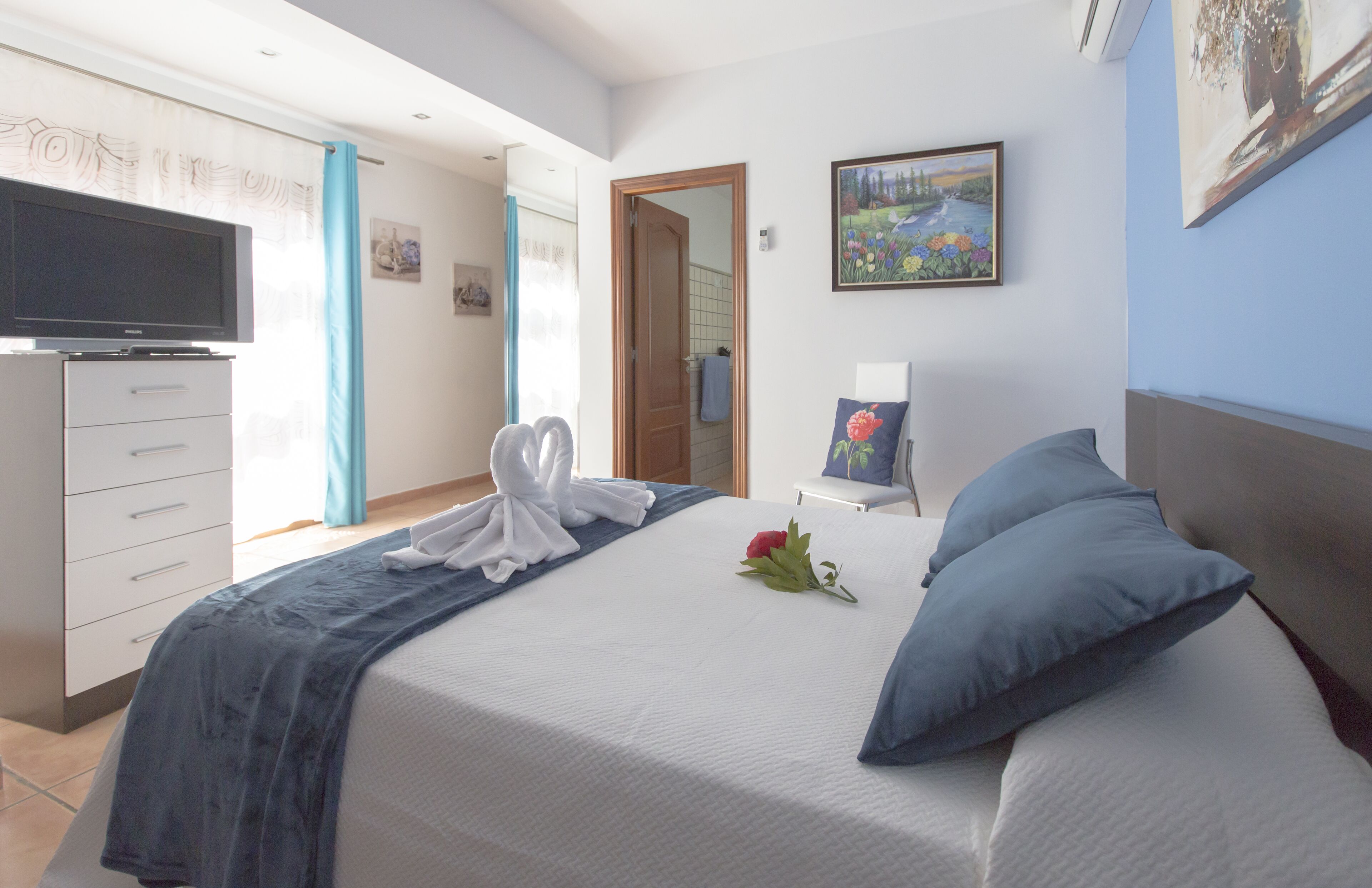 Une chambre d’hôtel avec un lit, une télévision, un bureau et un tableau au mur.