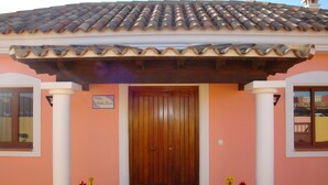 A building with a tiled roof, a wooden door, and two potted plants. -  VILLA "BELLA LUCIA 1" PRIVATE HEATED POOL, WIFI, BARBECUE, SATELLITE TV  (corralejo- la oliva)