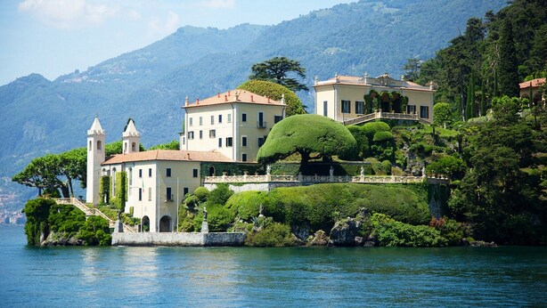A historic building with multiple stories, a tower, and a well-maintained garden with a large tree. - “For a perfect and UNFORGETTABLE GIFT … (Sala Comacina)