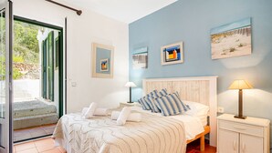 A bedroom with a bed, a nightstand, a cabinet, and a view of the outdoors. - Casa Lavanda (Fornells, Menorca)