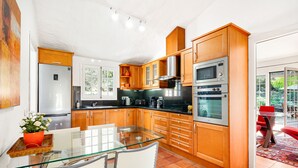Une cuisine moderne avec des meubles en bois, des appareils électroménagers en acier inoxydable et une table à manger en verre.