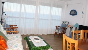 Ein Wohnzimmer mit einer Couch, Sesseln, einem Esstisch und einem Deckenventilator.