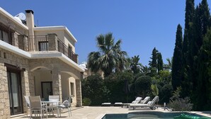 A swimming pool with inflatable shark toys, lounge chairs, and a stone building with a balcony. - Beautiful Stone Villa with large pool, close to beaches plus free use of car : ) (Coral Bay, Peyia)