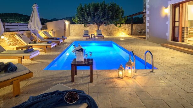A swimming pool area with lounge chairs, a table with drinks, and a lantern. - Kalypso Villa, a Serene Family Retreat with Pool (Rethymno)